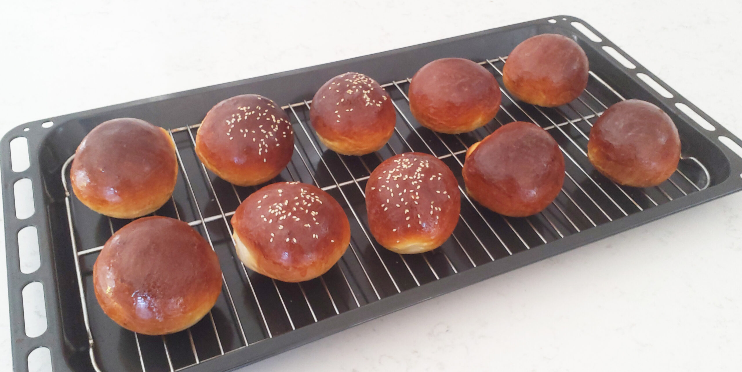 Freshly baked soft milk burger buns cooling on a rack